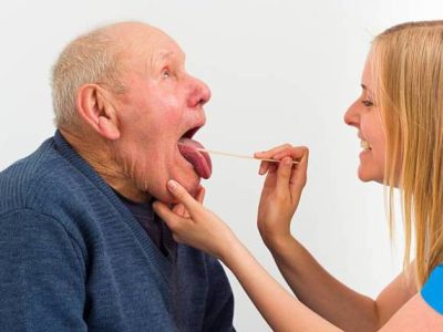 دکتری که گلوی پیرمردی را معاینه می کند.