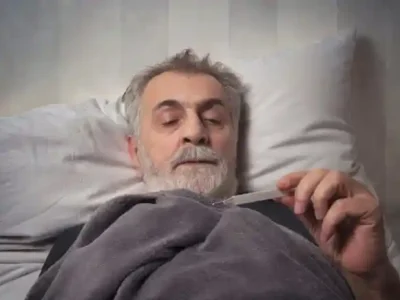فردی که دارد به درجه تب نگاه می کند.